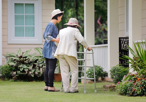 A nurse helps a woman outside and adult family home