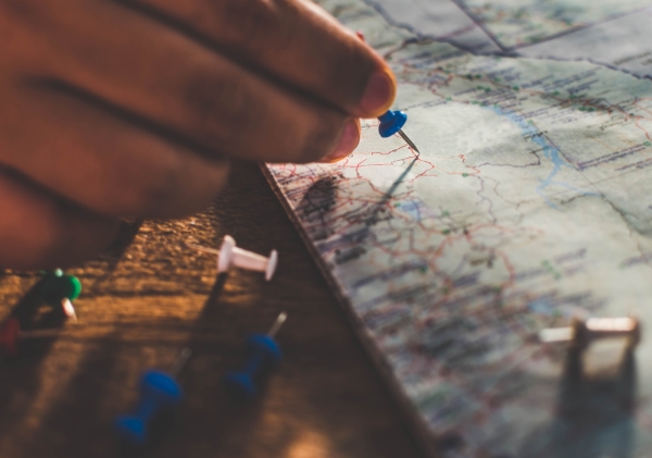 A person placing a pushpin on a map