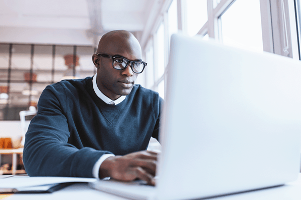 man with glass working on a computer