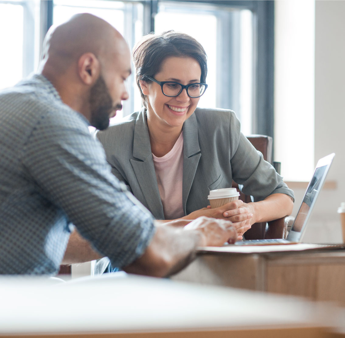  two people working over laptop